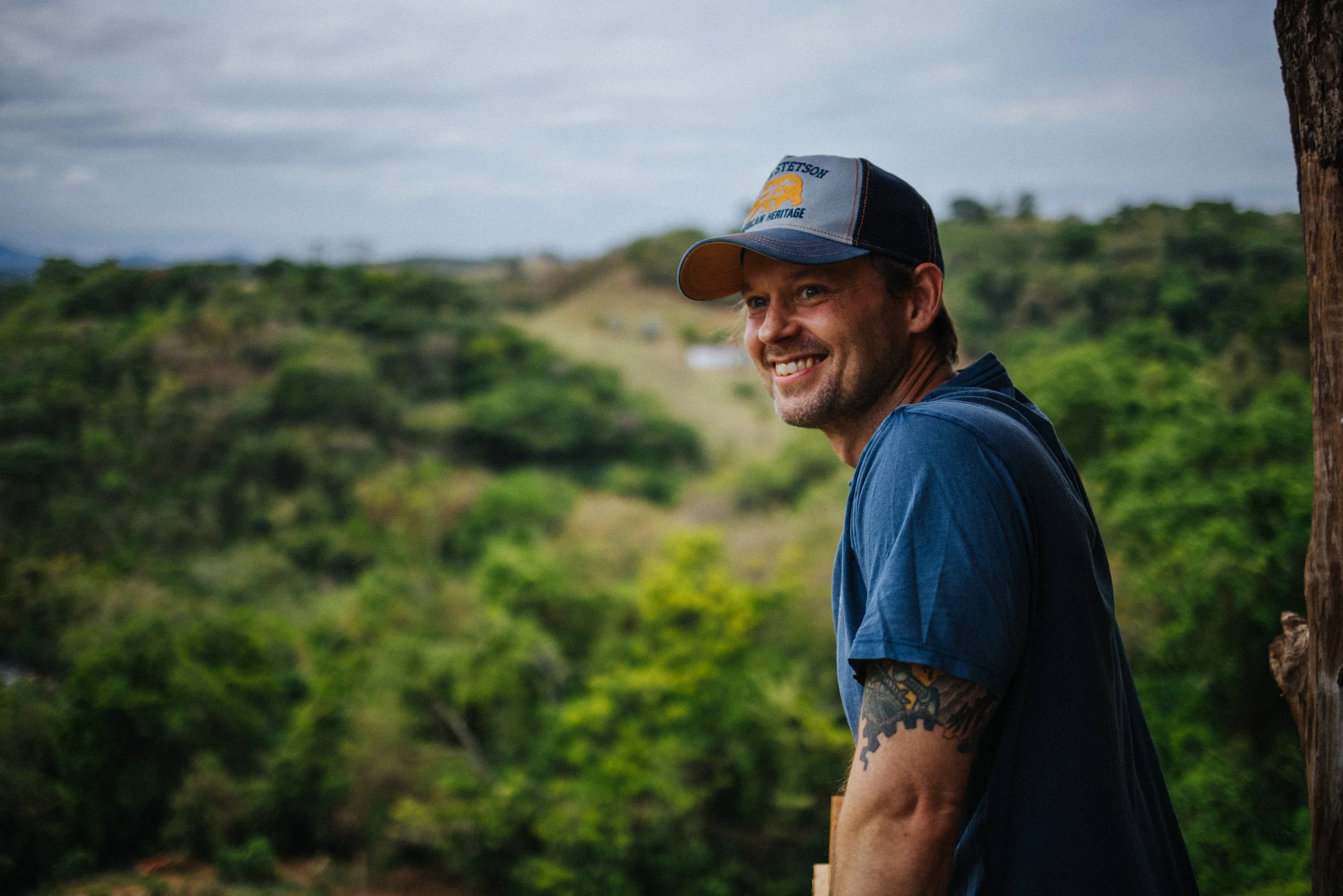 Robin Danehav smiling in green hills in Brazil, on a coffee documentary trip.